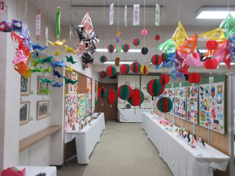 入居者の作品を展示した共用スペース。折り紙やアート作品が天井から吊るされ、壁に飾られている。